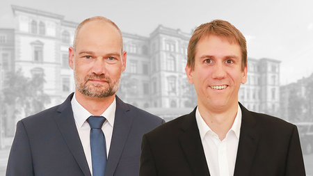 A middle-aged man and a younger man look directly at the camera.