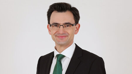 Photo of a man in th emiddle ages wearing glasses with a suit and tie.