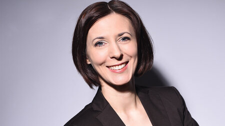 A young woman in a blazer smiling