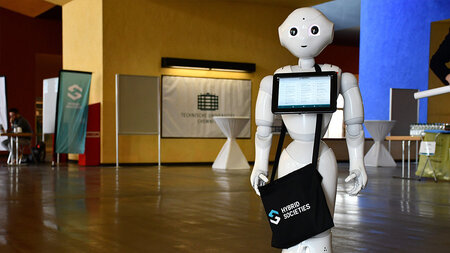A roboto holfs a bag with the logo of the CRC.
